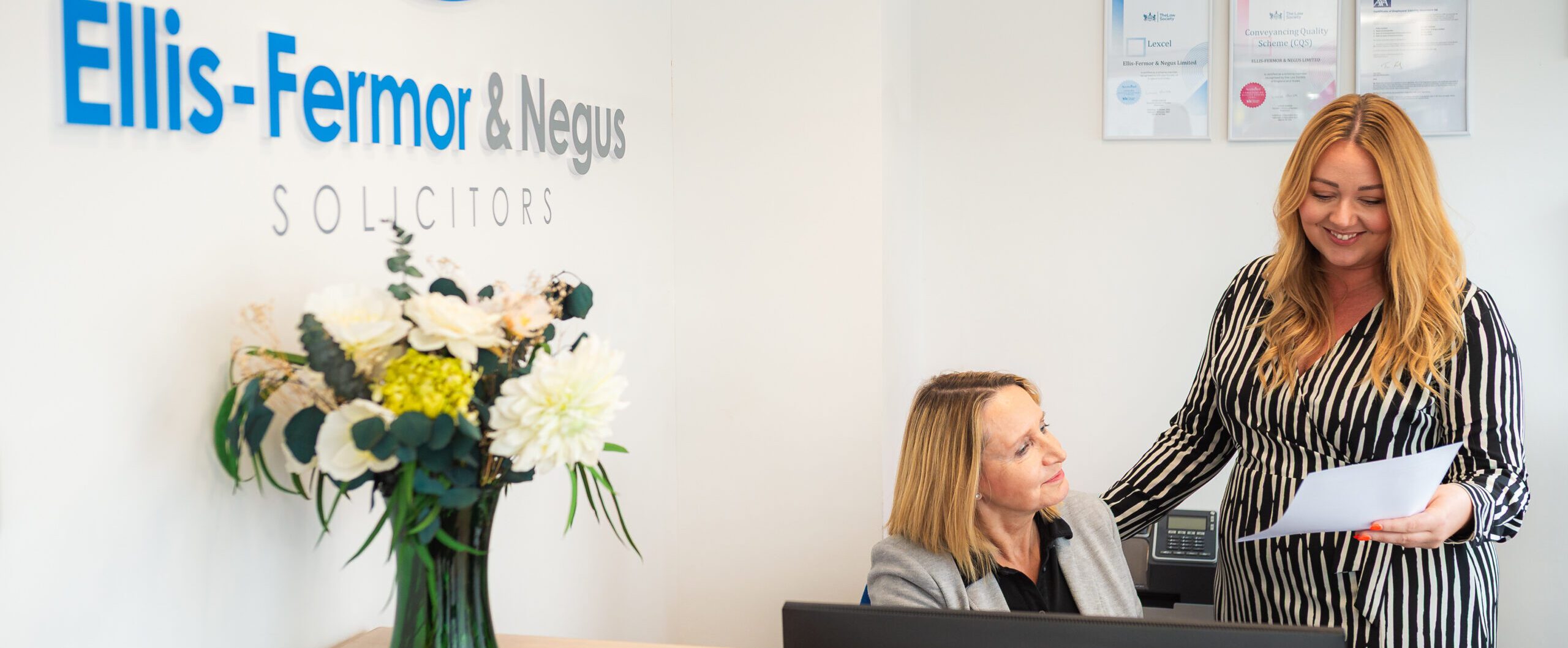 A friendly interaction between solicitors at Ellis-Fermor & Negus, showcasing approachability and professionalism in a legal office environment.