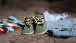 Green baby shoes and surrounding baby clothes