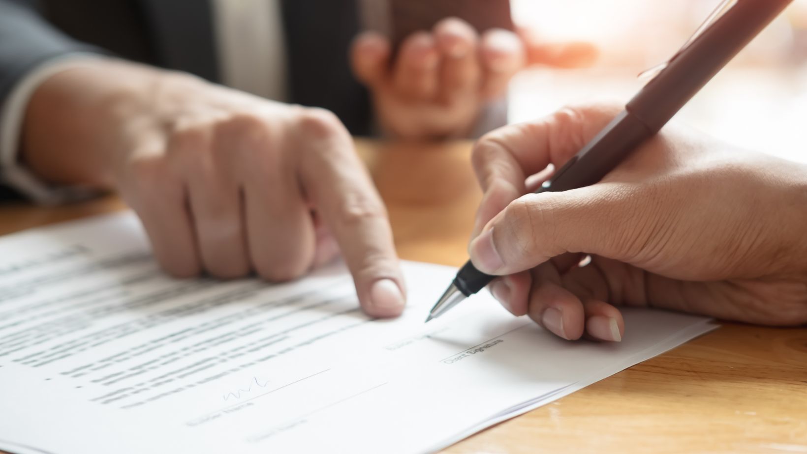 Two people completing paperwork at a desk