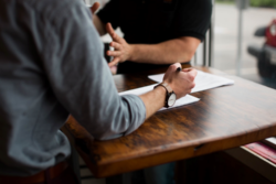 Two men discussing business at a table with paperwork