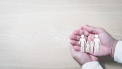 Close up of a pair of hands holding paper cut-out of family