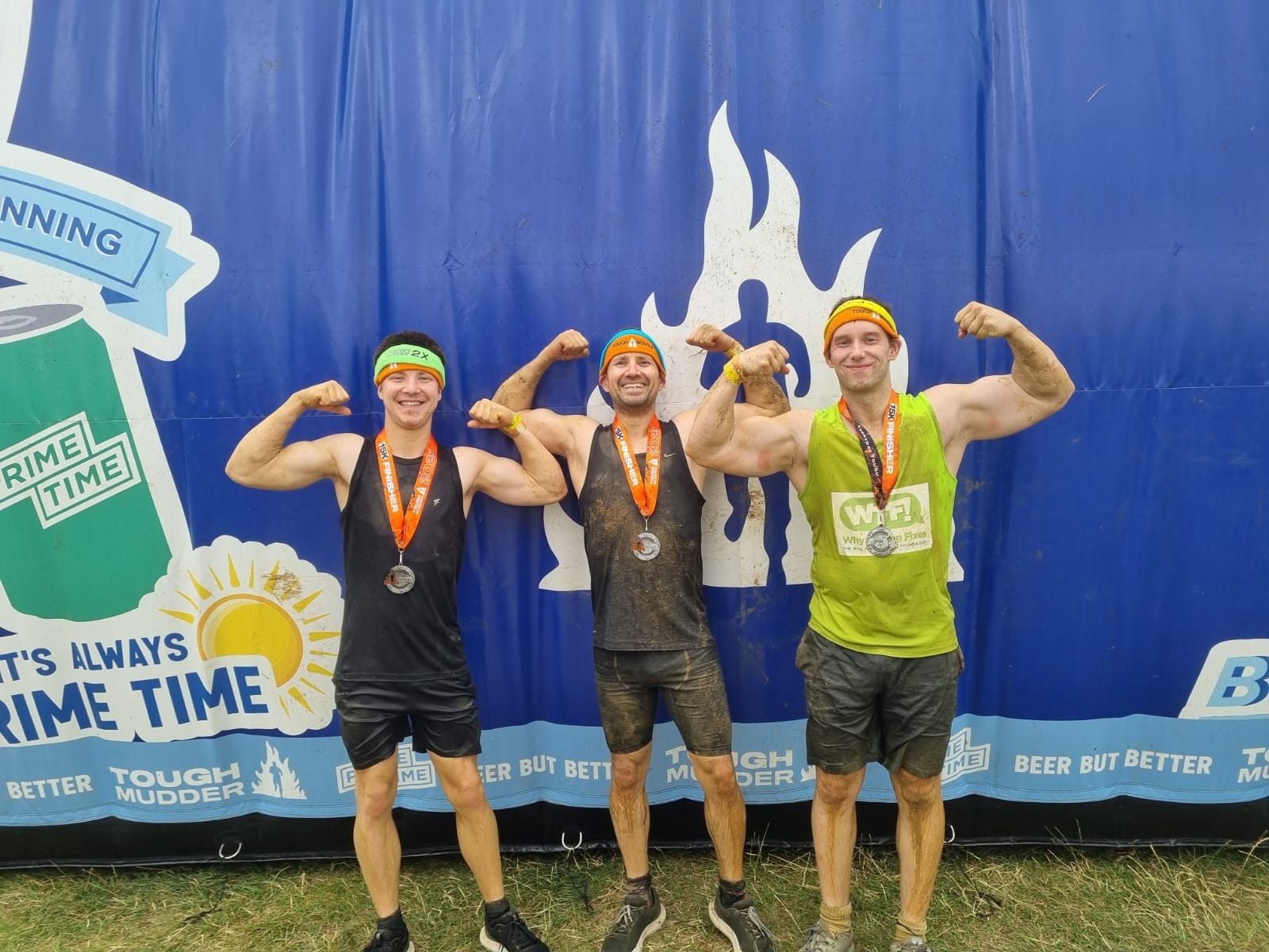 Three happy young men covered in mud after race