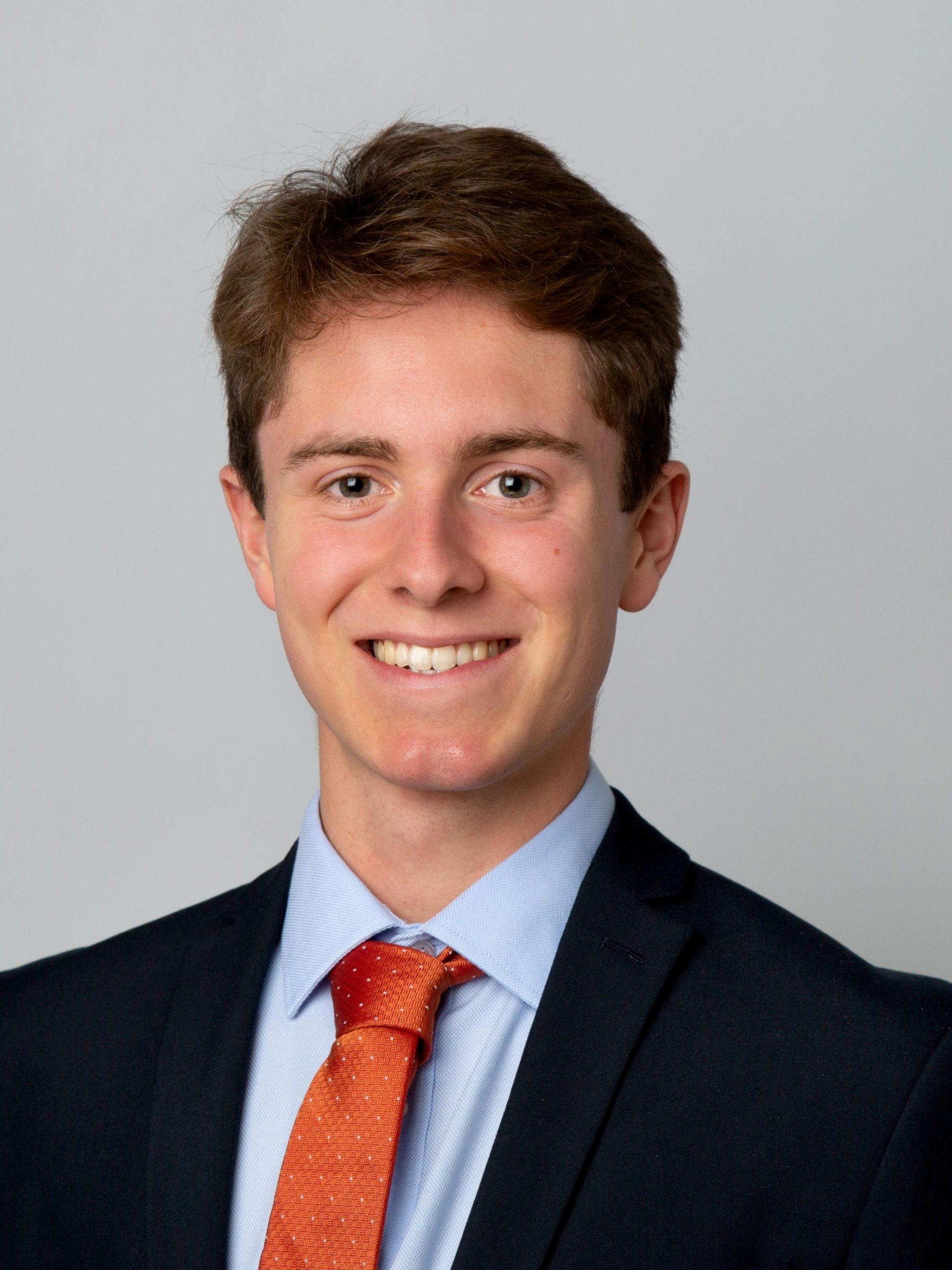 Smiling young solicitor in a formal suit and orange tie, representing Ellis-Fermor & Negus law firm.