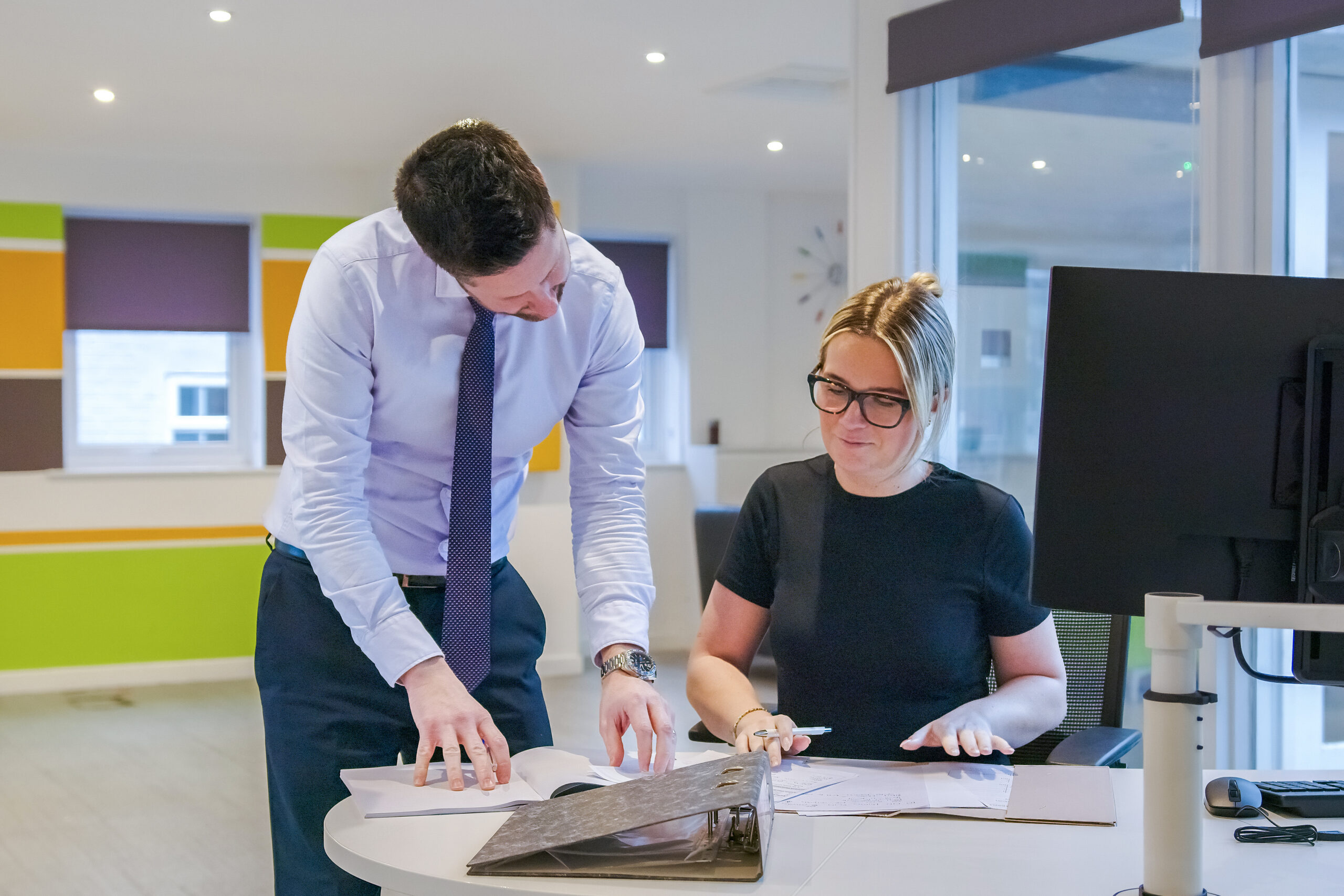 A solicitor assisting a colleague with paperwork in a modern office setting, highlighting attentive legal advice at Ellis-Fermor & Negus in the East Midlands.