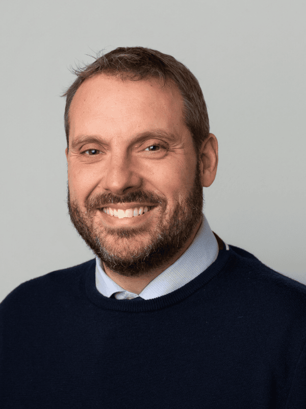 Smiling male solicitor in a navy sweater, representing an East Midlands law firm providing legal services