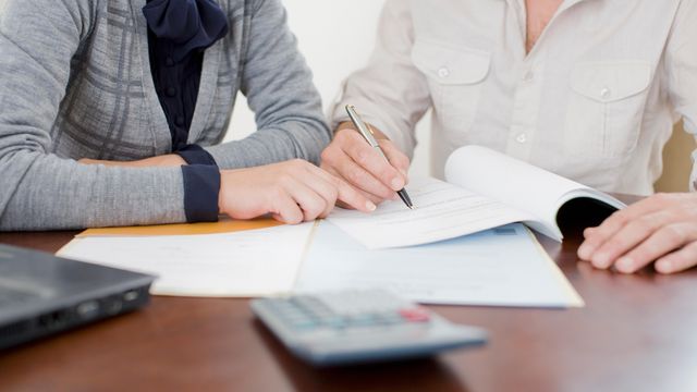 Clients receiving legal advice from solicitors at Ellis-Fermor & Negus, reviewing important documents on a desk.