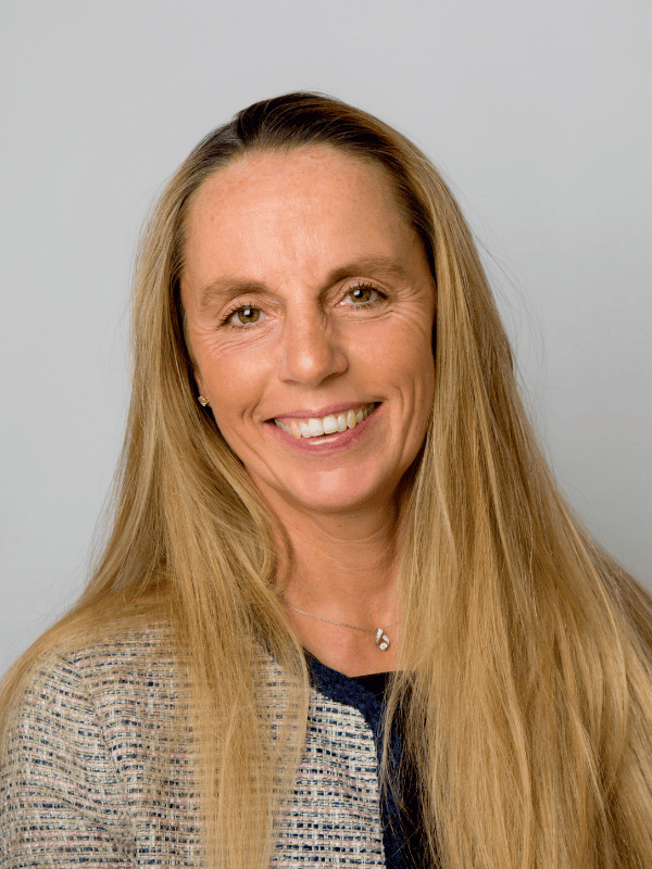 Headshot of a smiling female solicitor with long hair, wearing a blazer, suitable for legal services representation.