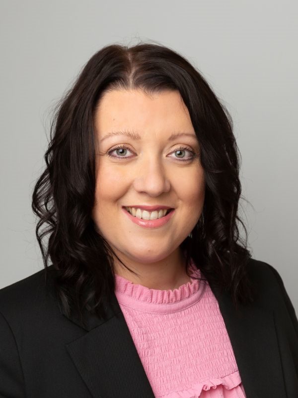 Female solicitor with curly hair and a pink blouse, representing Ellis-Fermor & Negus, delivering approachable legal advice in the East Midlands.