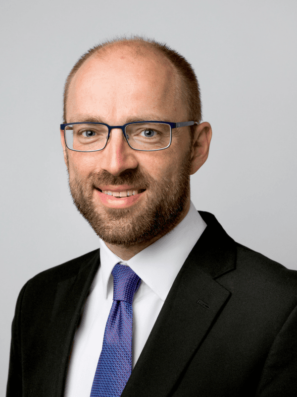 A professional solicitor from Ellis-Fermor & Negus, an East Midlands solicitors’ firm, smiling in a black suit and blue tie with glasses.