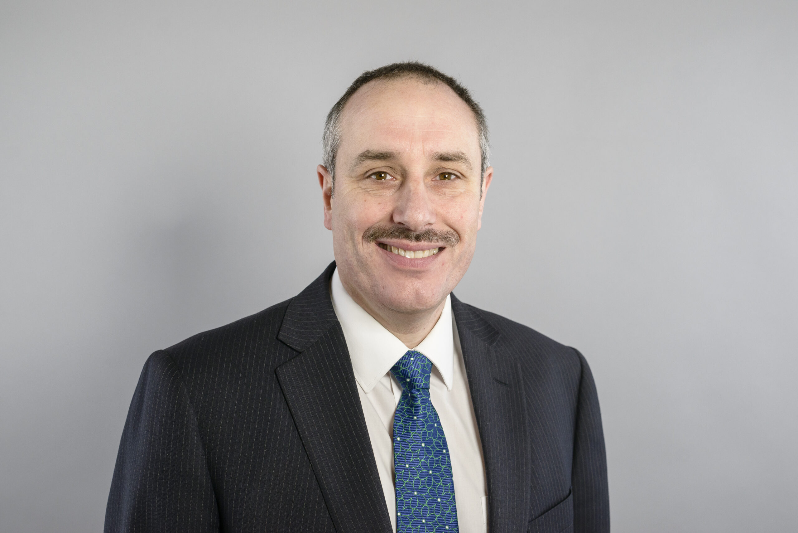 A smiling male solicitor in a dark suit and patterned tie, representing Ellis-Fermor & Negus, an East Midlands solicitors' firm providing legal advice.
