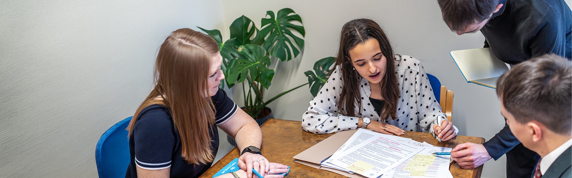 A group of professionals discussing legal documents at a table in an office setting, representing an approachable legal consultation at Ellis-Fermor & Negus solicitors.